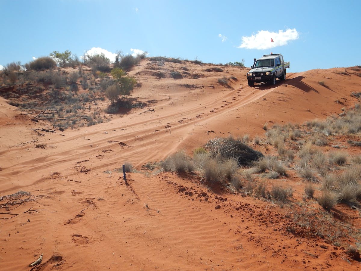 Landcruiser 70 driving down a red sand dune