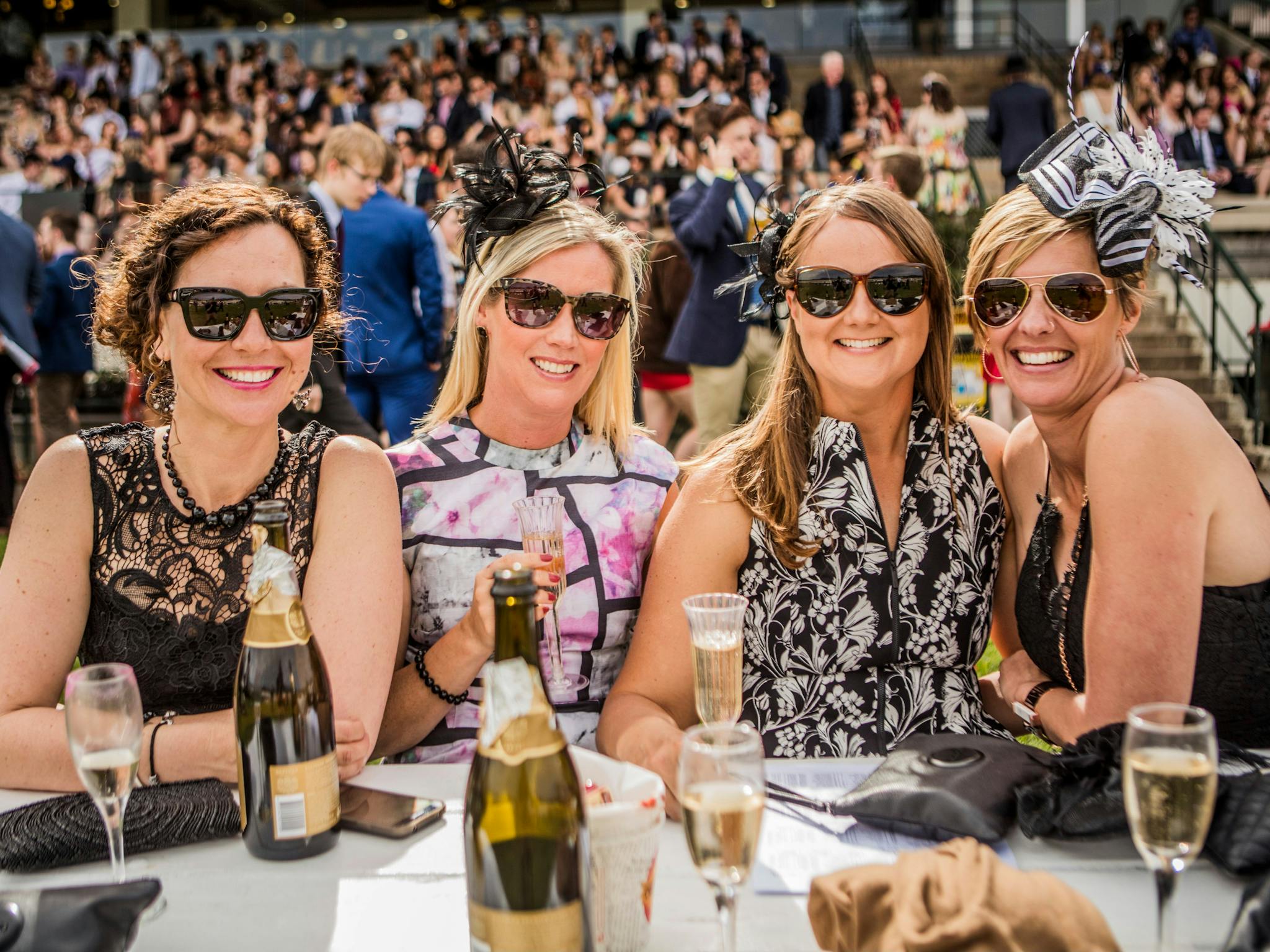 Four ladies dressed for the races enjoying champagne