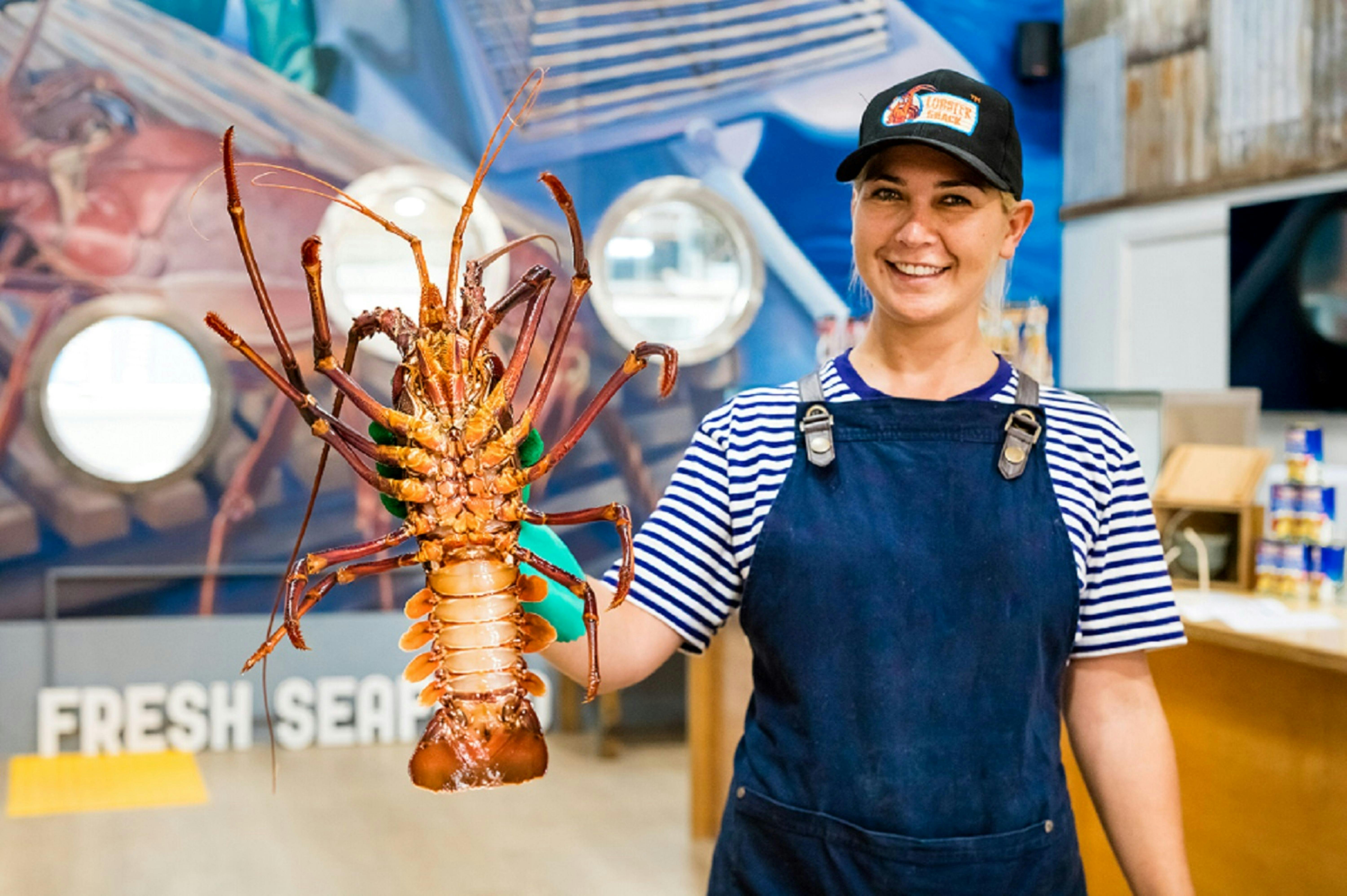Lobster Shack tour guide holding up a live jumbo Lobster in the factory