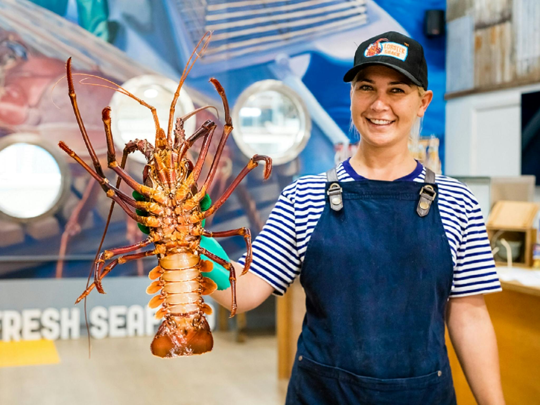 Lobster Shack tour guide holding up a live jumbo Lobster in the factory