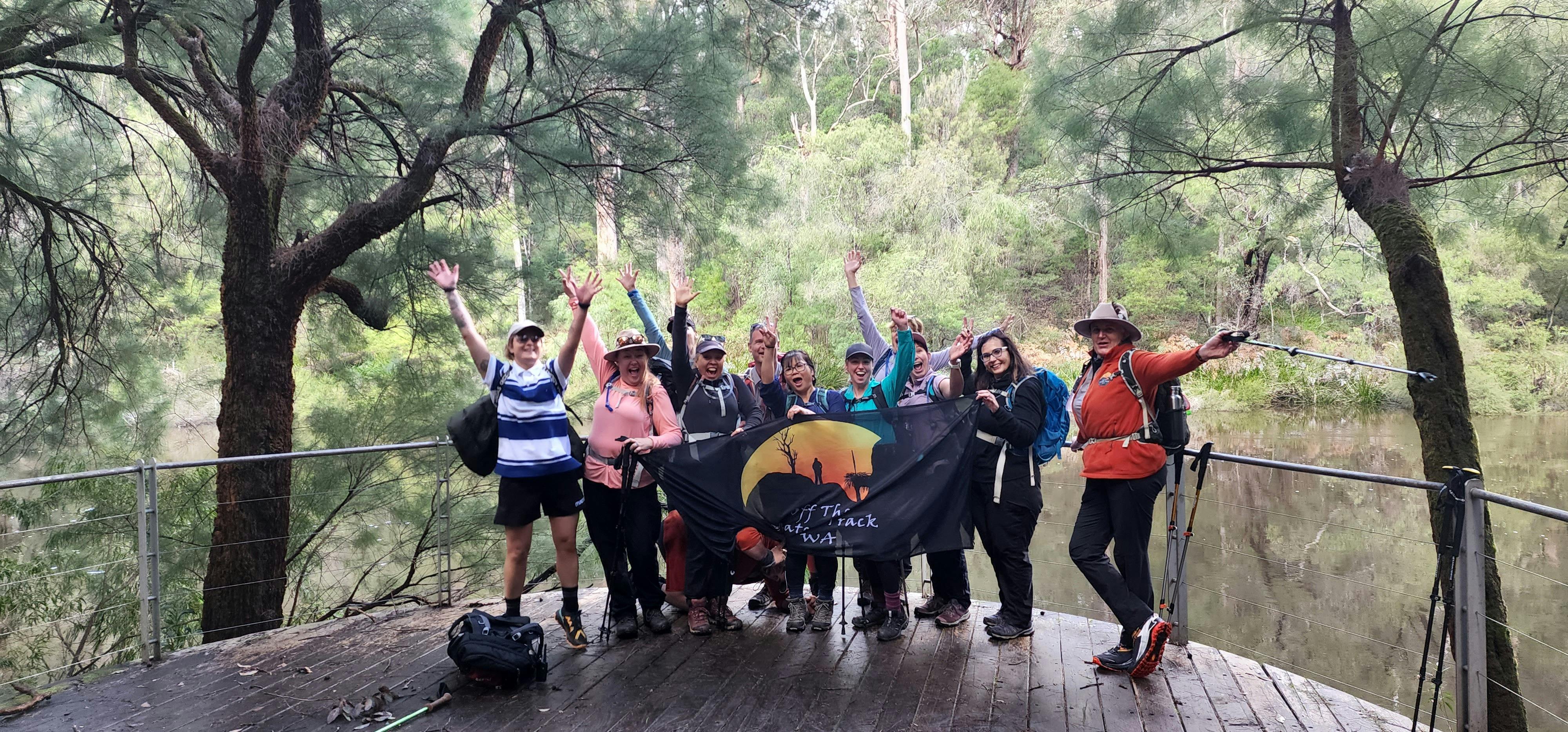 A group of hikers posing for a photo with Off The Beaten track banner