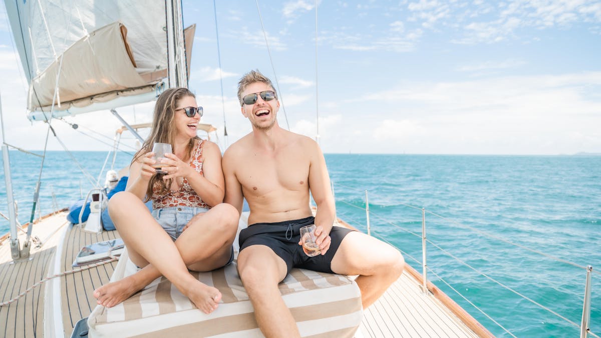 Couple laughing at the front of a yacht with a non-alcoholic cocktail in hand