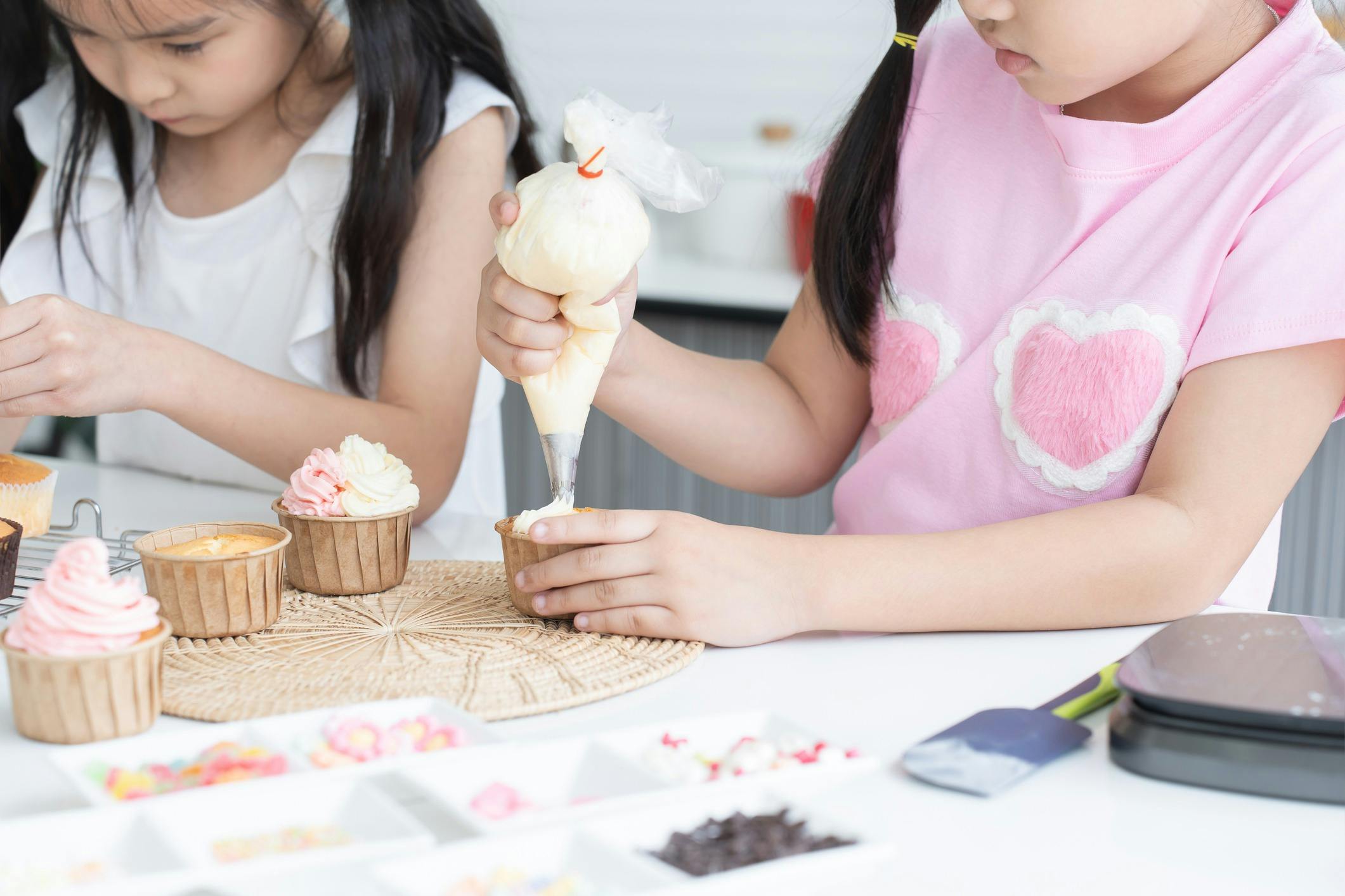 Young kids icing cupcakes.