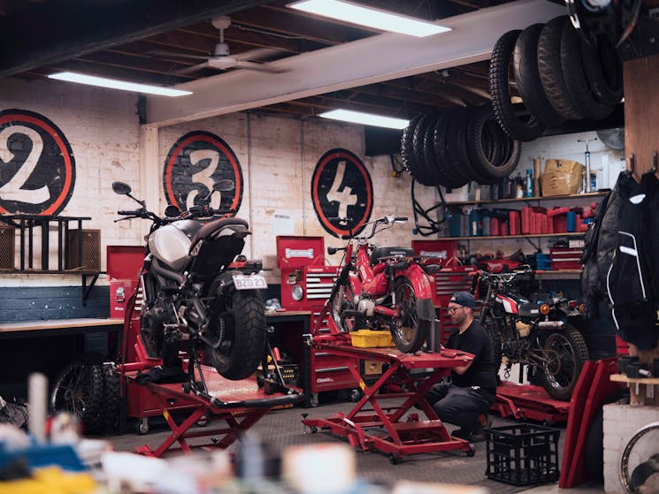 Man working on his motorcycle at the Rising Sun Workshop