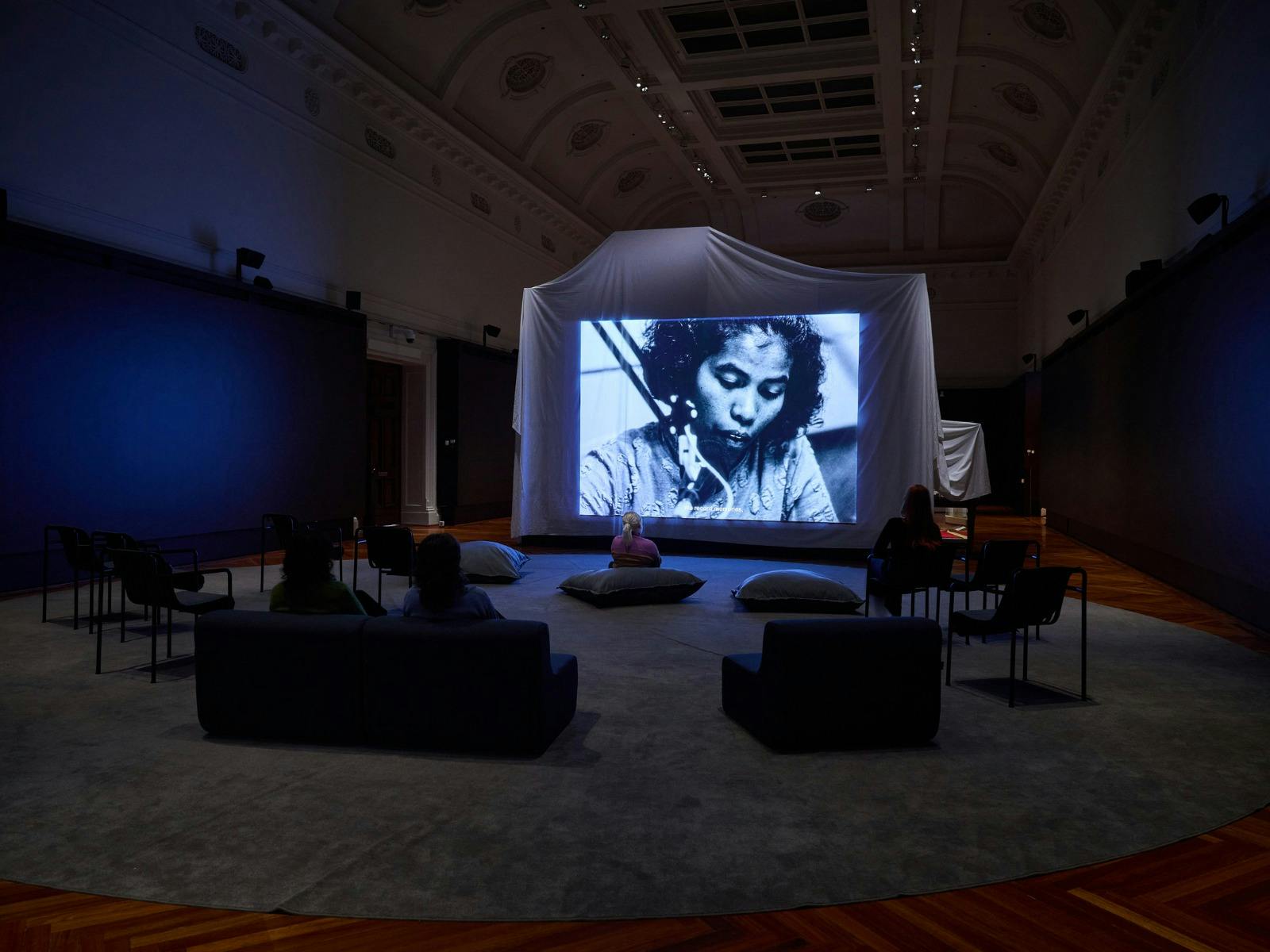 People sitting around a screen watching a film
