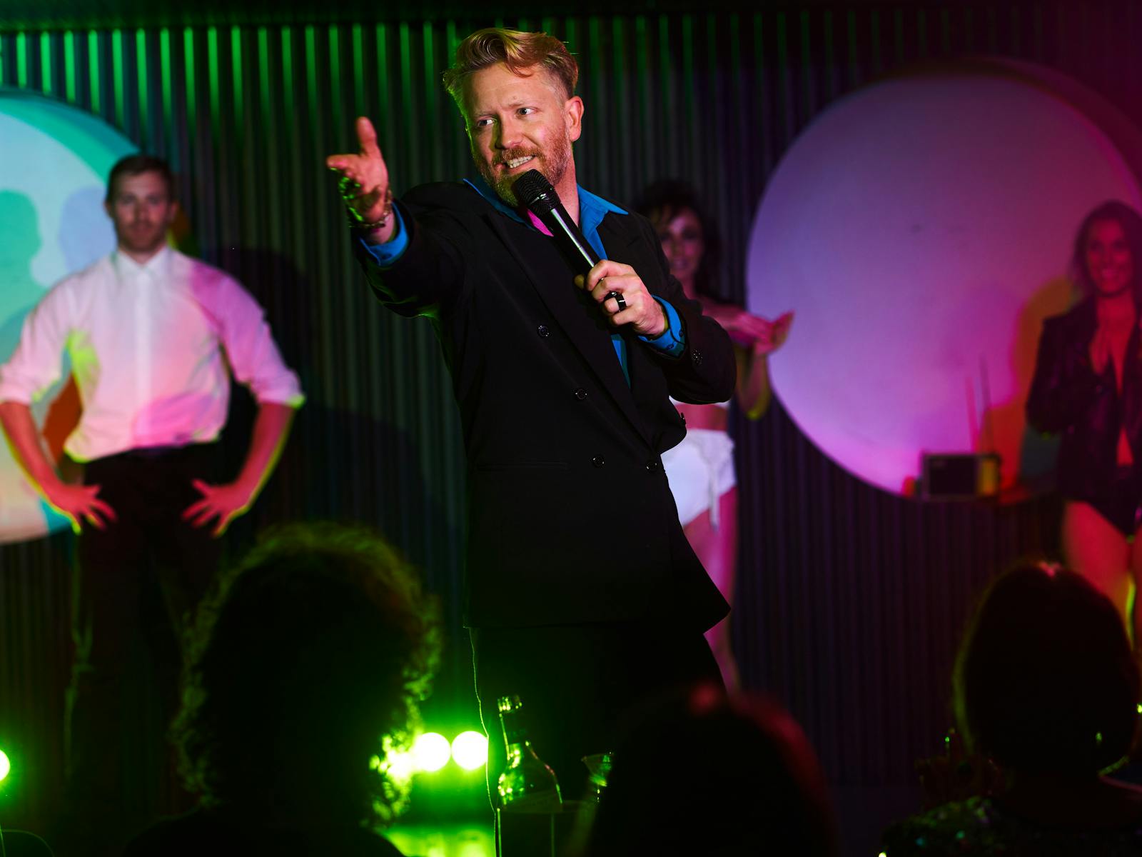 Sydney comedian MC for cabaret show in Potts point performs live on stage, reaching to the crowd.