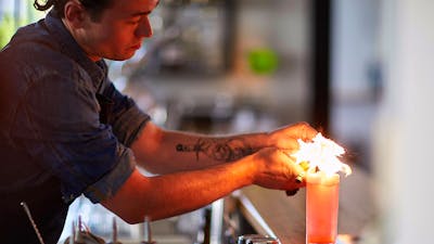 Barman lighting a cocktail on the bar
