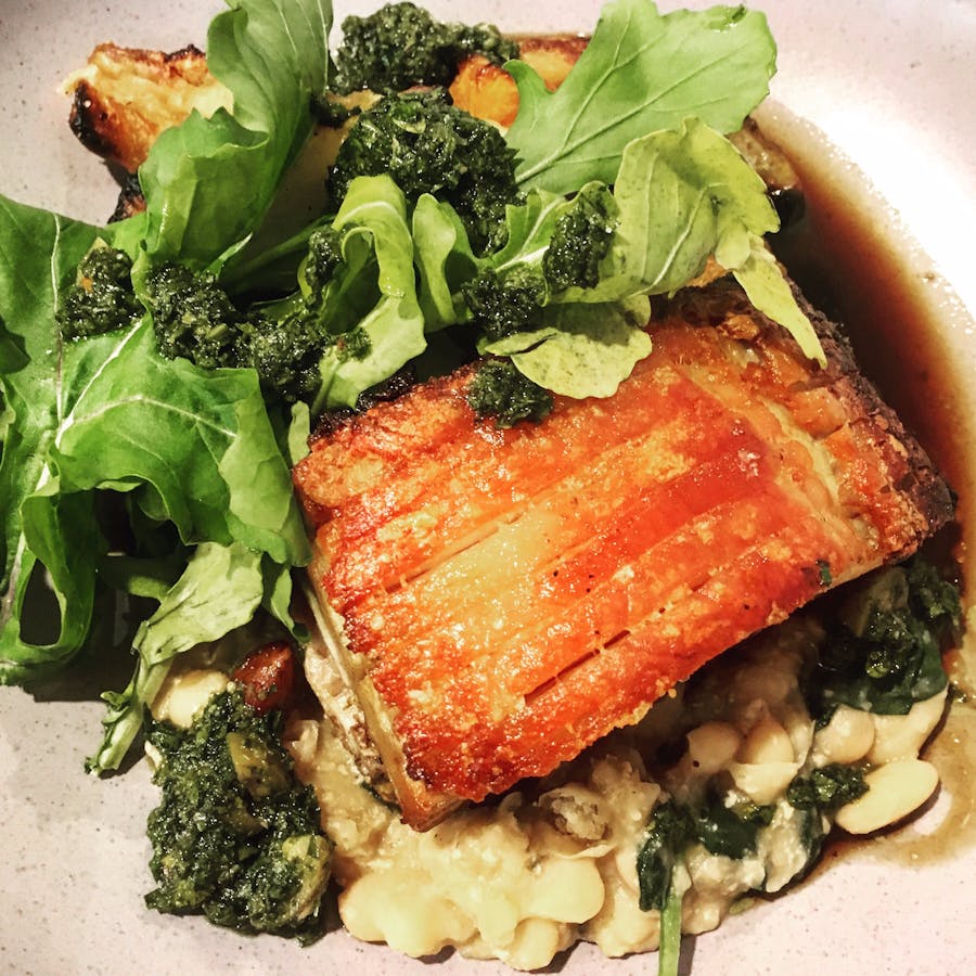 Milk braised pork belly with white beans, winter vegetables, rocket, gremolata