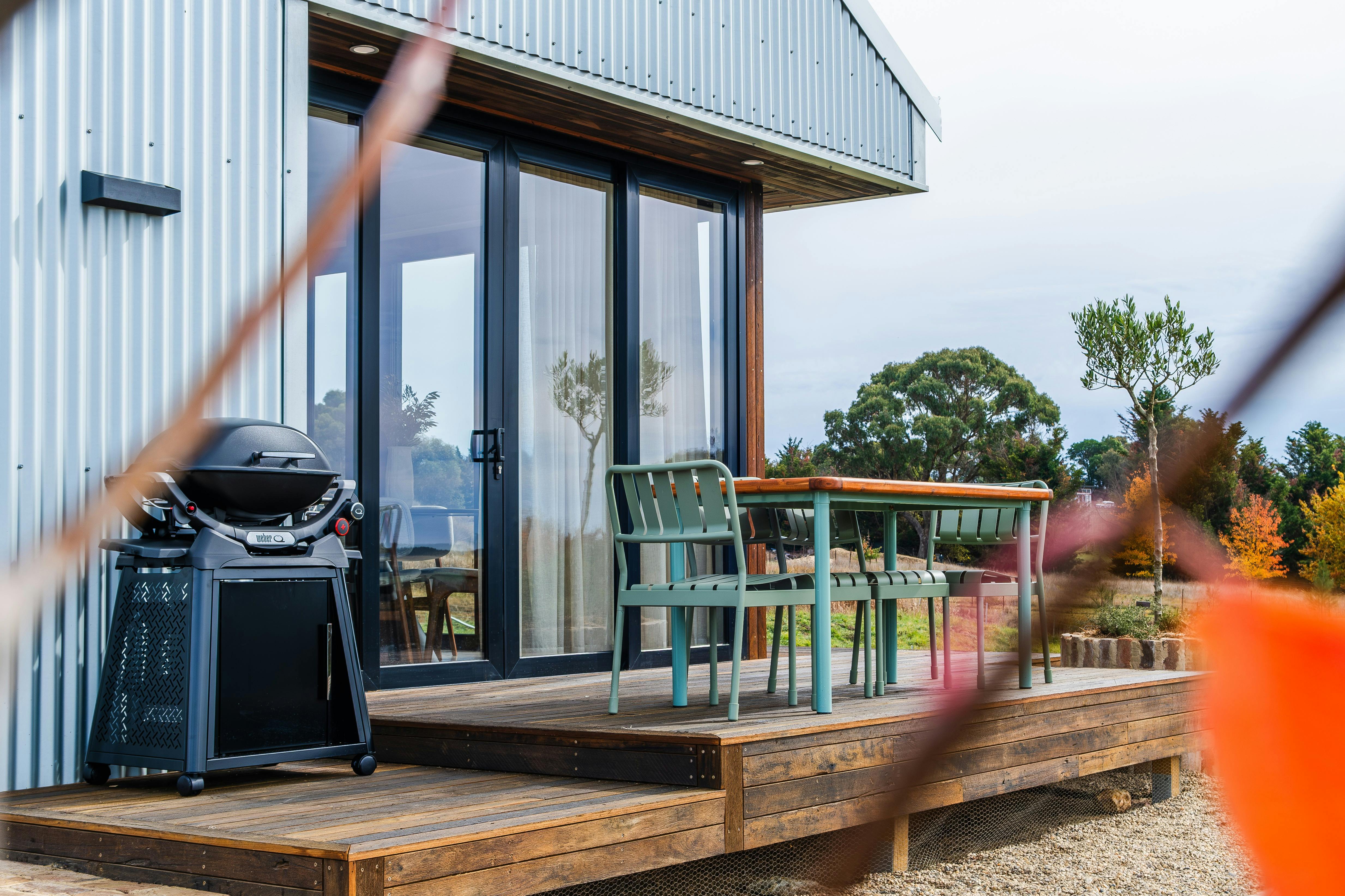 An outdoor verandah and deck with a BBQ and dining table visible.