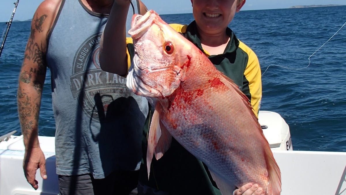 Young angler holding up his catch of a Red Throat Emperor, with another angler standing behind him.