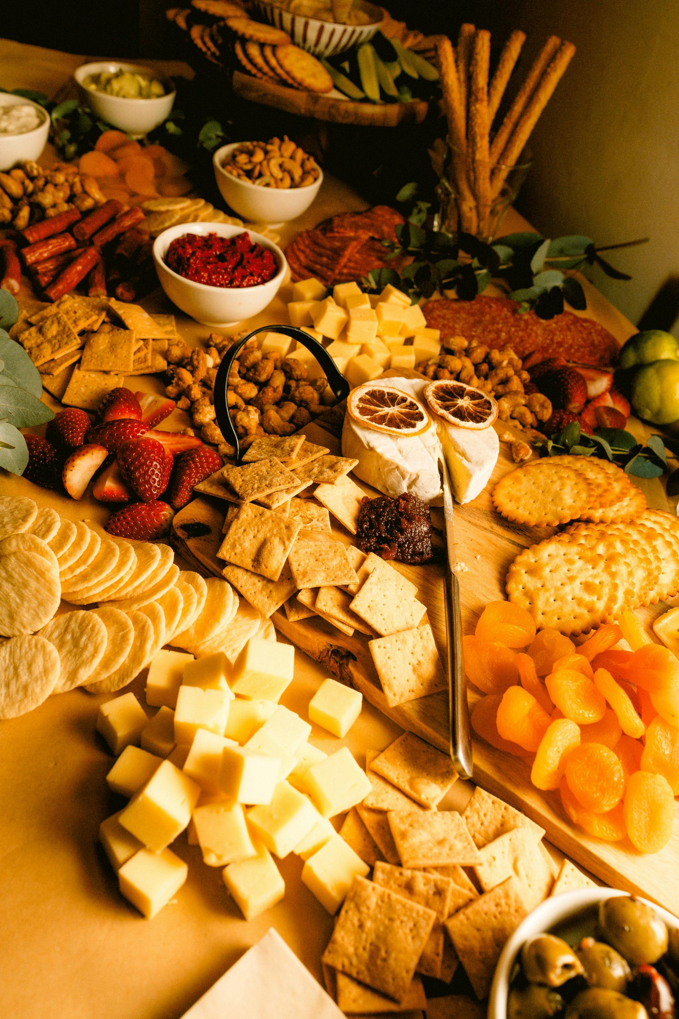 Grazing table with crackers, cheese, dried fruit, dips, nuts, and fresh strawberries