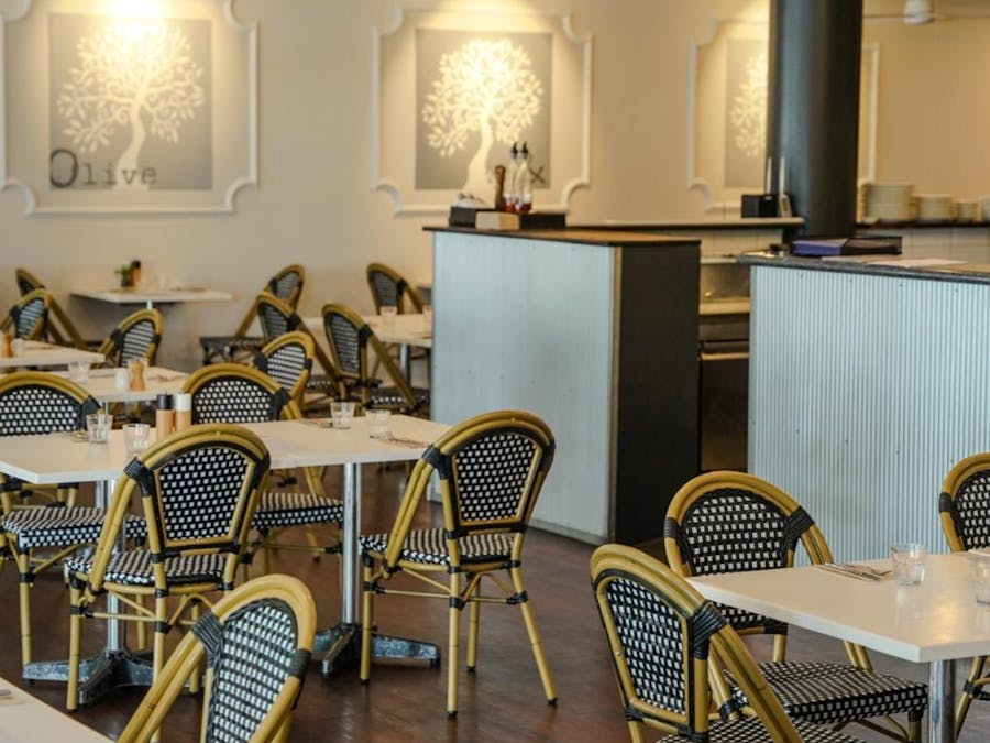 Cafe table and chairs set around room with timber floorboards and silver look counter