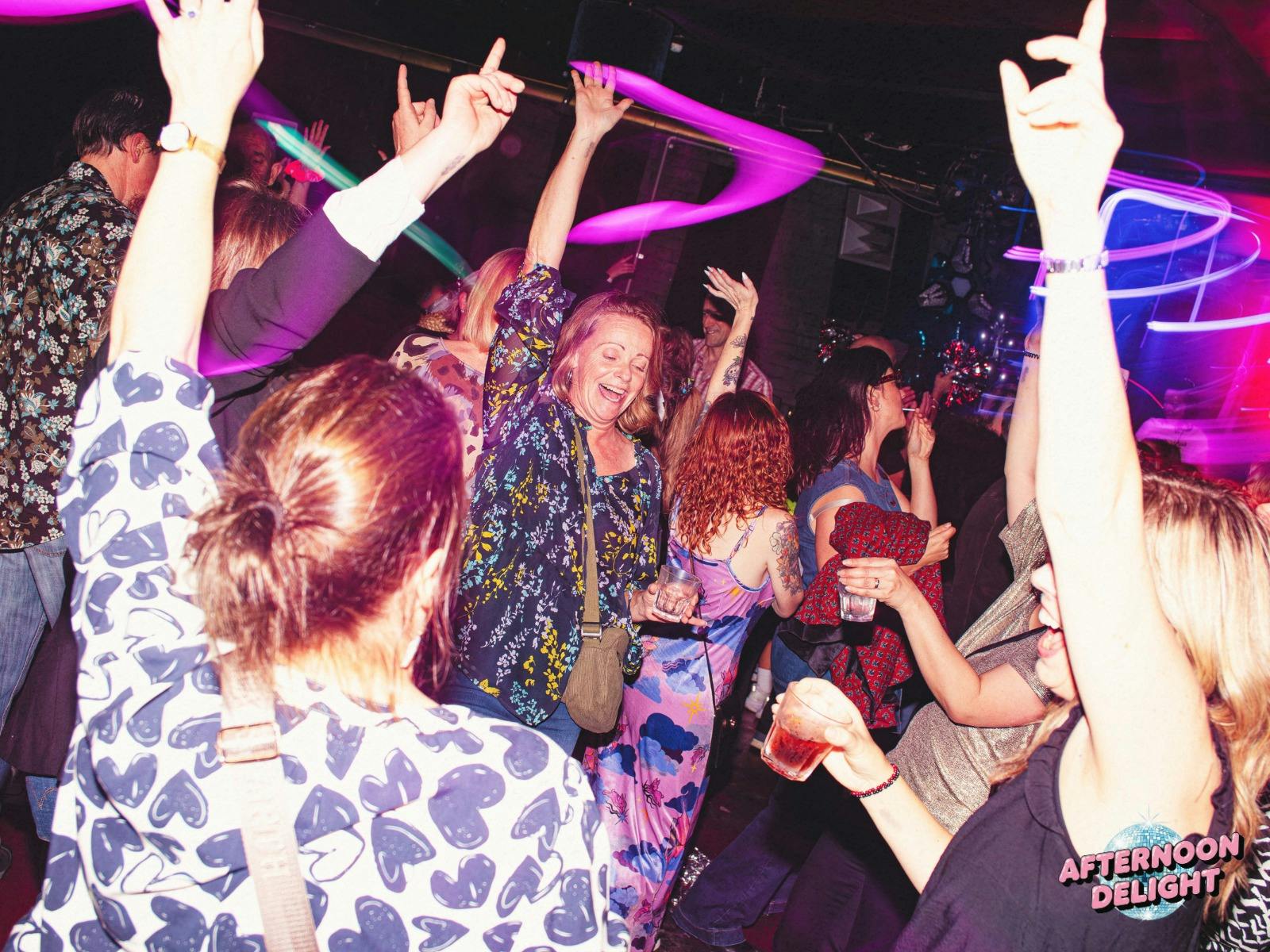 Image shows lively dancefloor crowd with hands in the air, mix of age groups