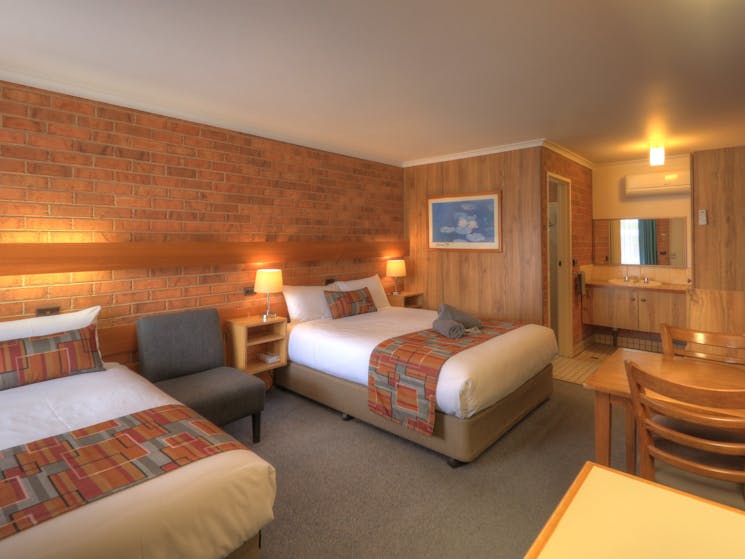 Deluxe twin room showing one queen bed and one single bed, table & chairs