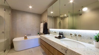 Bright apartment bathroom with a white bathtub, tiled walls, and updated fixtures.