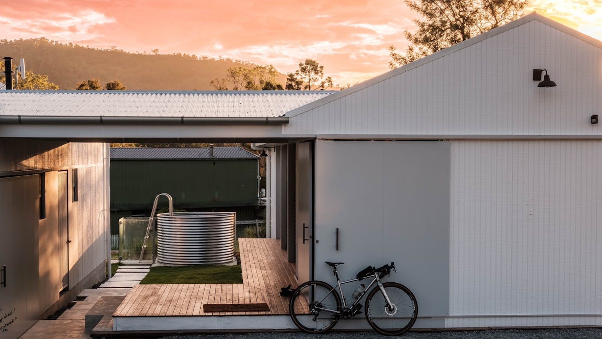 Rail Trail Refuge  accom with plunge pool in the background & bike leaning at front at sunrise