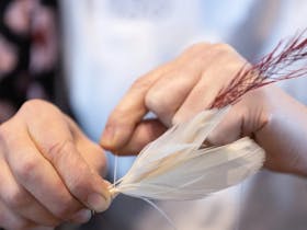 Close up image of hands weaving feathers