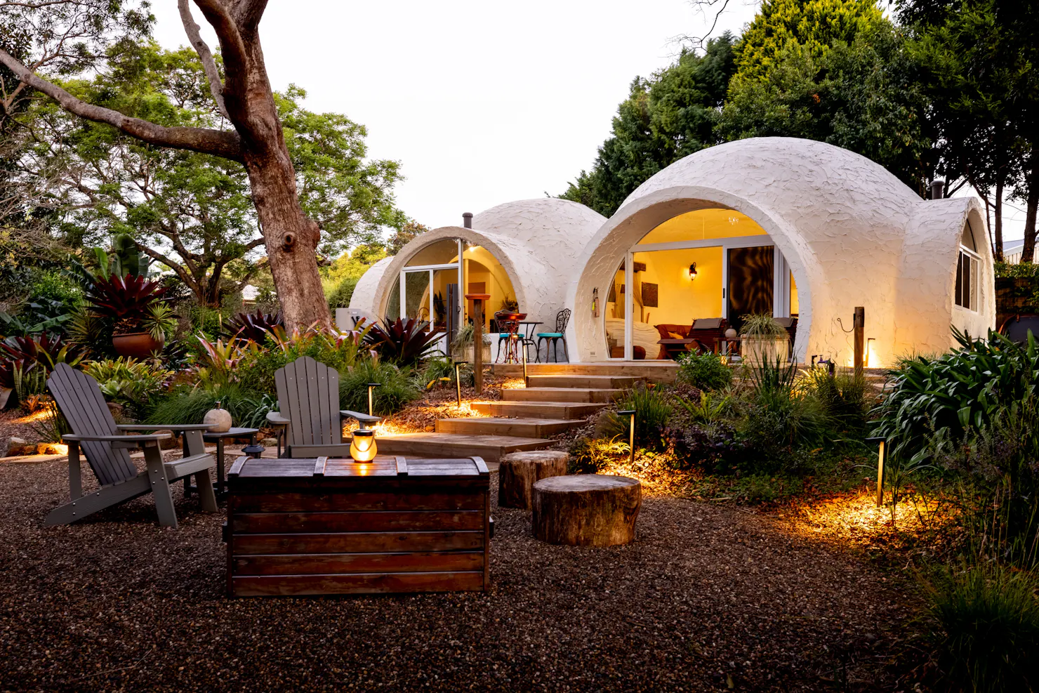 Hinterland Igloo surrounded by lush gardens with an outdoor fire pit and seating area.