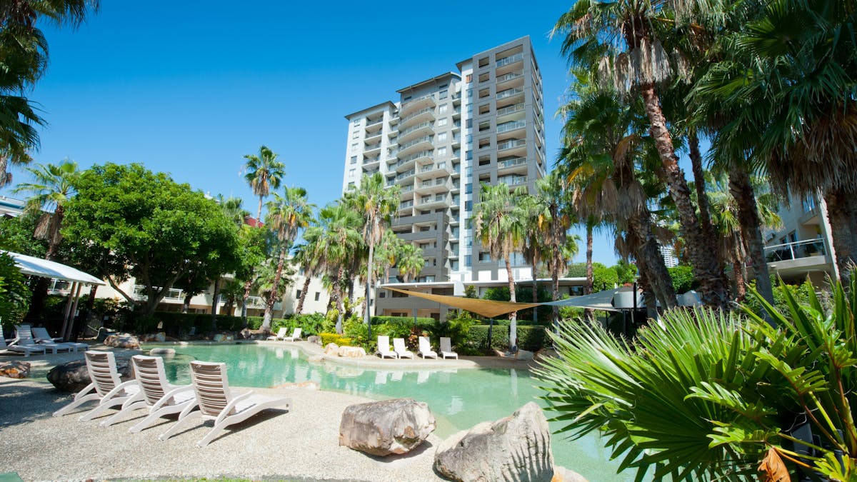 View of lagoon style pool with apartment building behind.