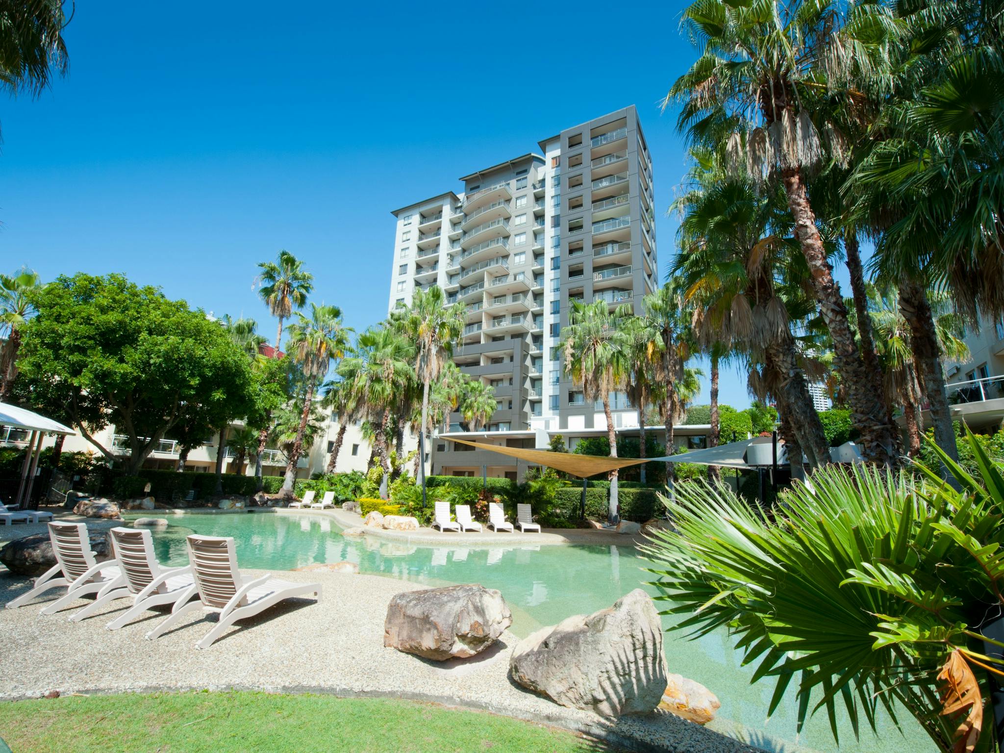 View of lagoon style pool with apartment building behind. View of lagoon style pool with apartment building behind.