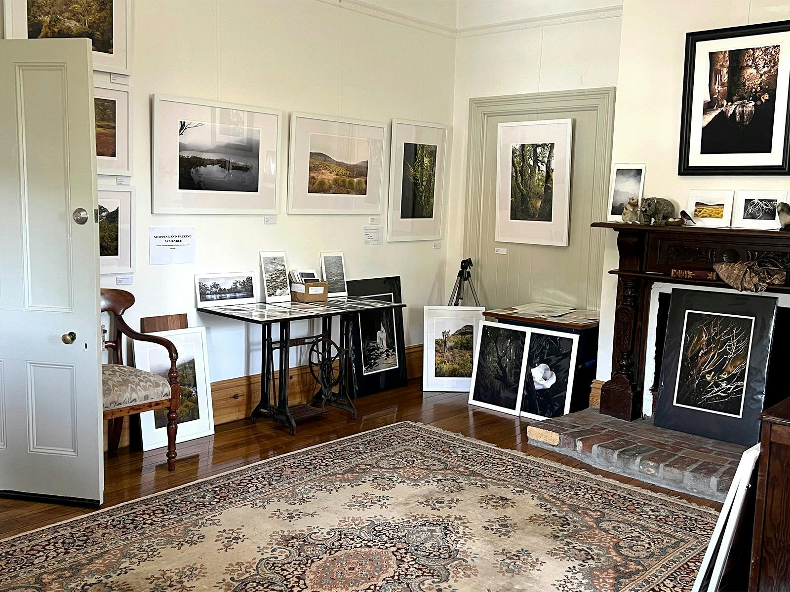 Interior of artist gallery studio in heritage home with artworks, mantle and large rug