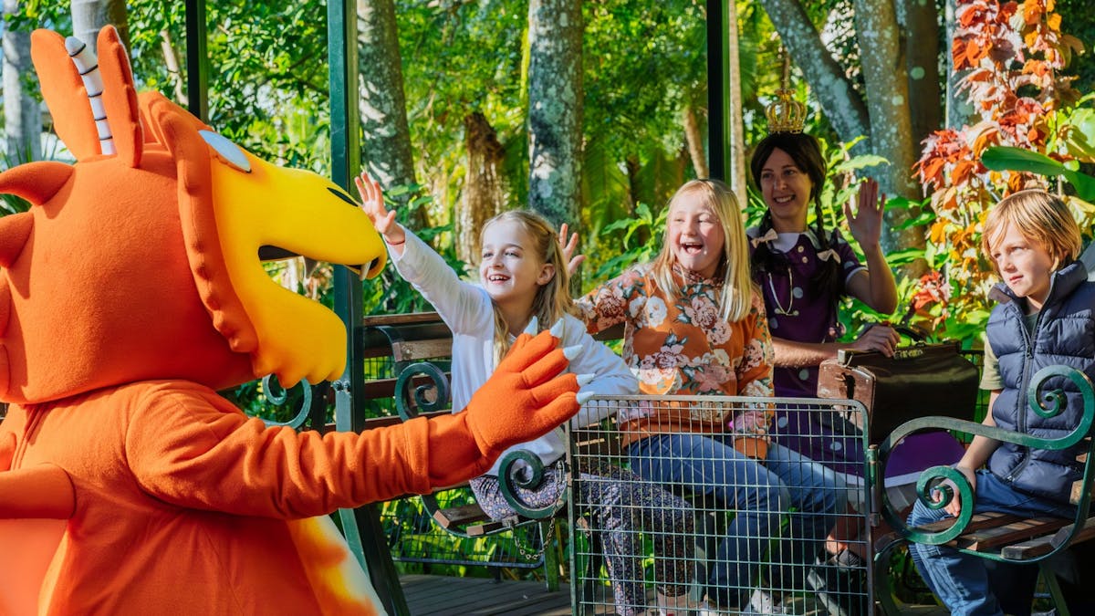 Orange Zog character waving to smiling kids on the train