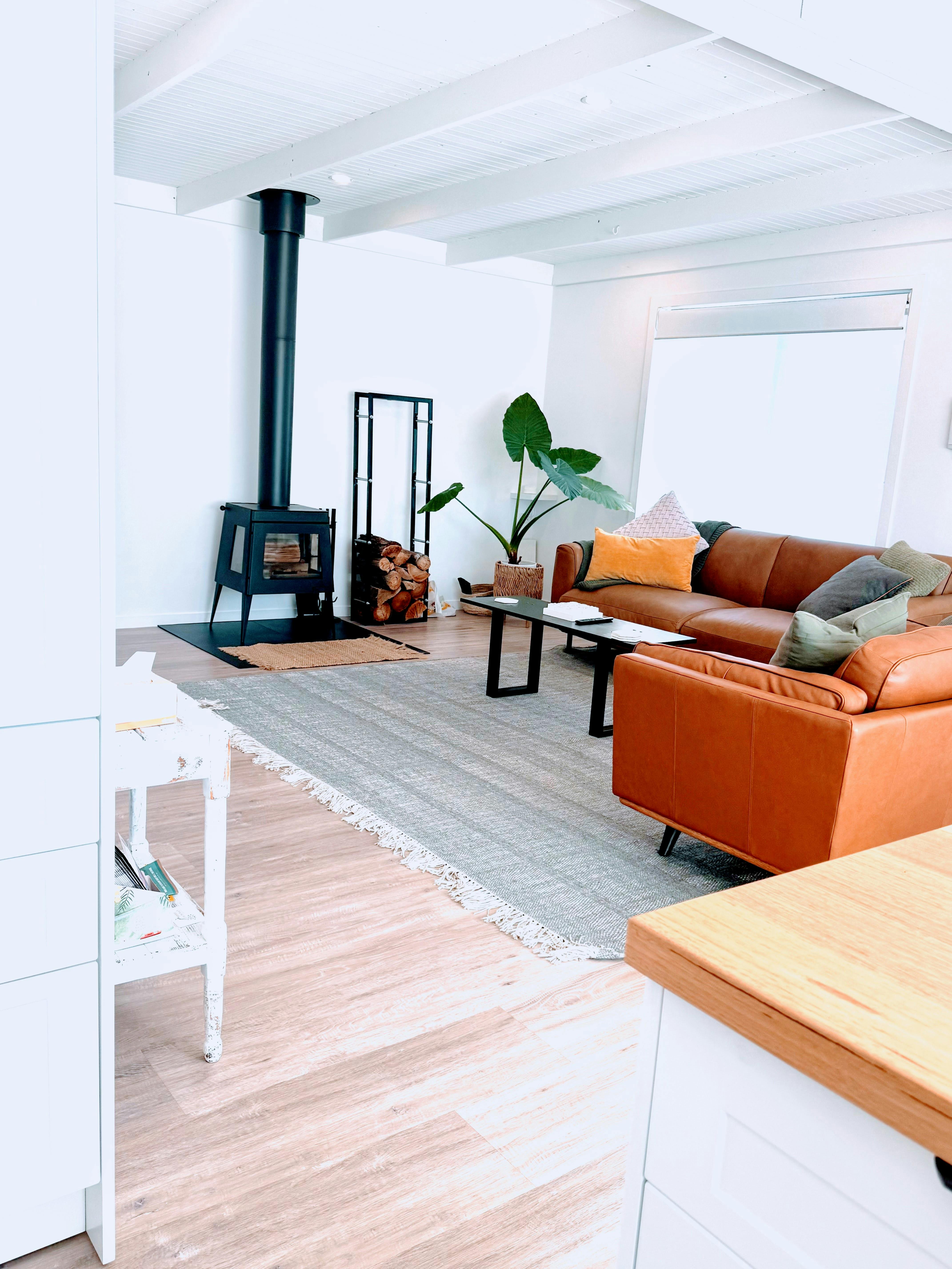 Stylish open plan living room with wood heater and comfortable leather sofas