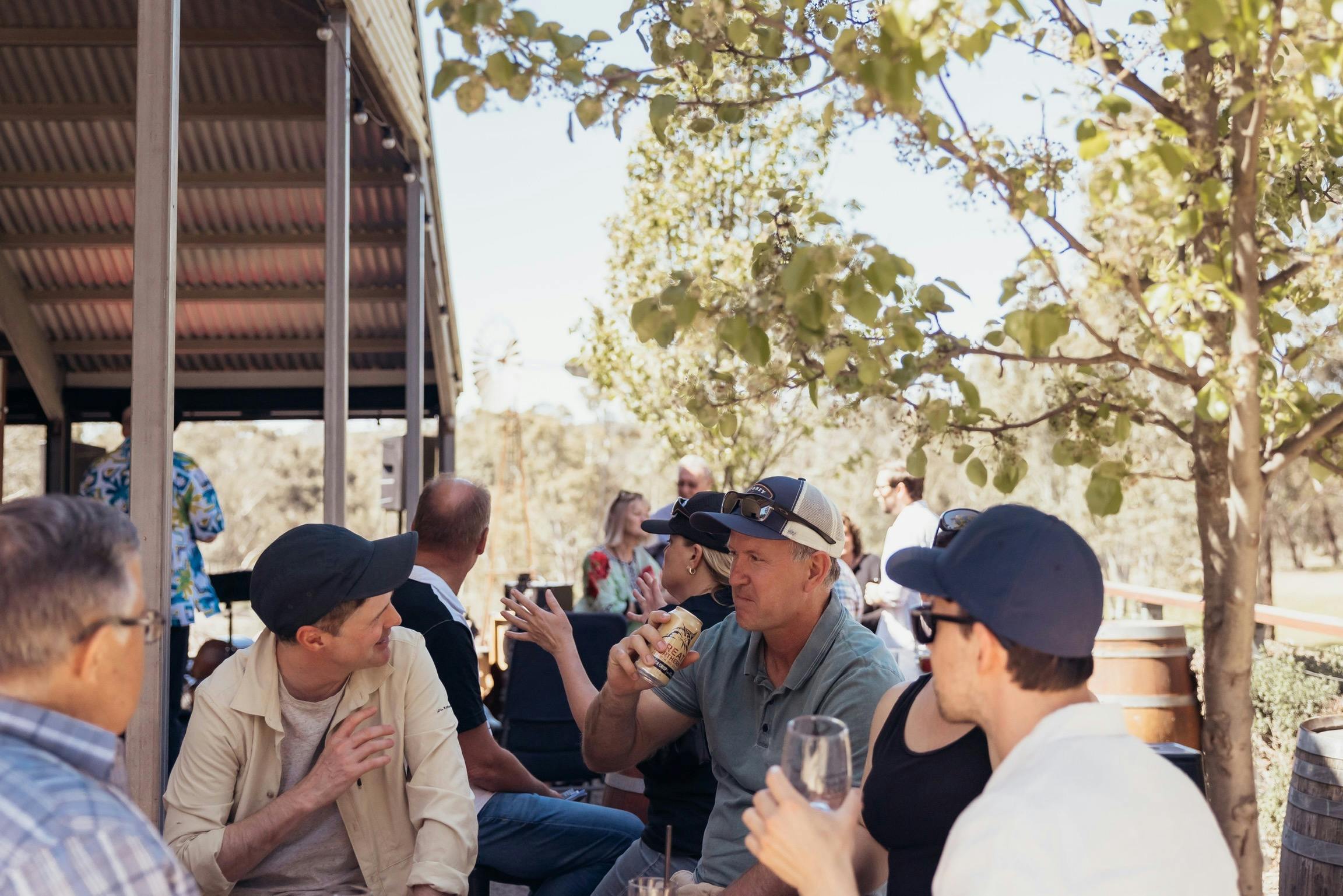 a group of guests enjoying sunshine and drinking around sine barrels