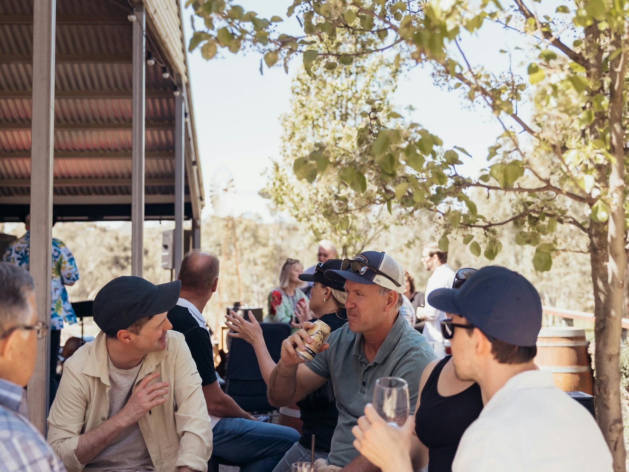 a group of guests enjoying sunshine and drinking around sine barrels