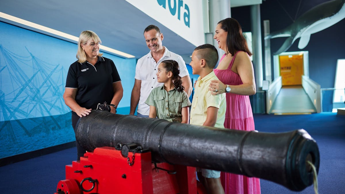 Family of 4 talking with museum guide next to a cannon