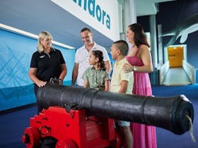 Family of 4 talking with museum guide next to a cannon