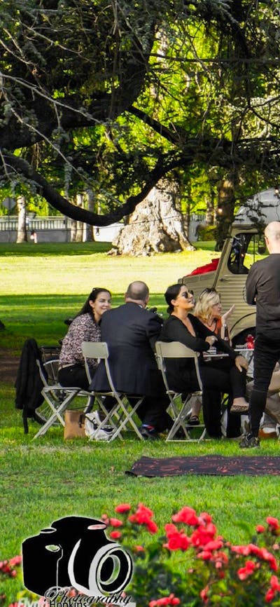 People standing and sitting on chairs and tables in front of van
