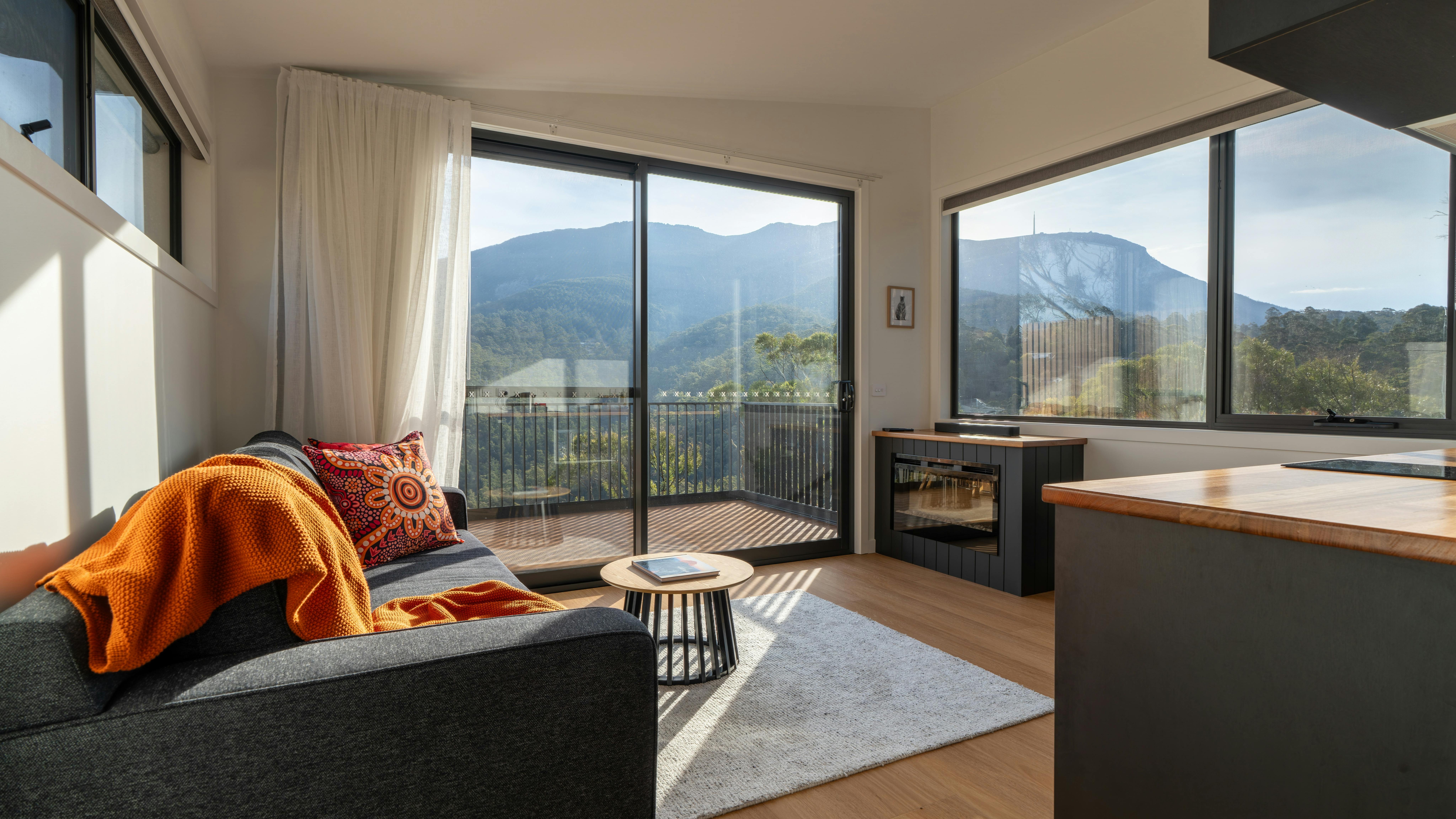 A warm living room with comfortable furnishings and big windows looking out to a mountain view