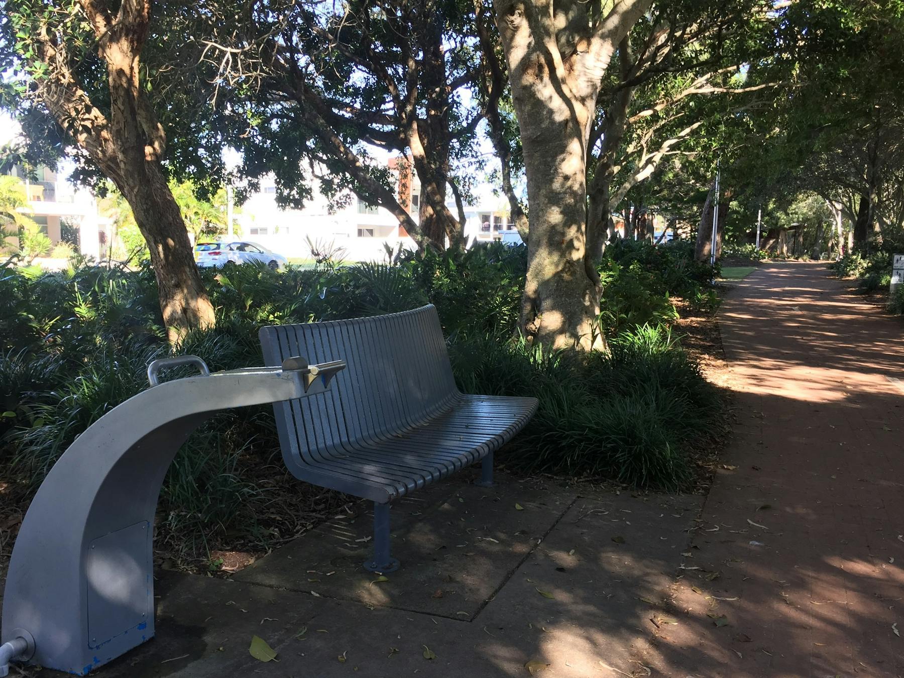 photo showing part of the Hervey Bay Coastal pathway with water station and bench seat under trees