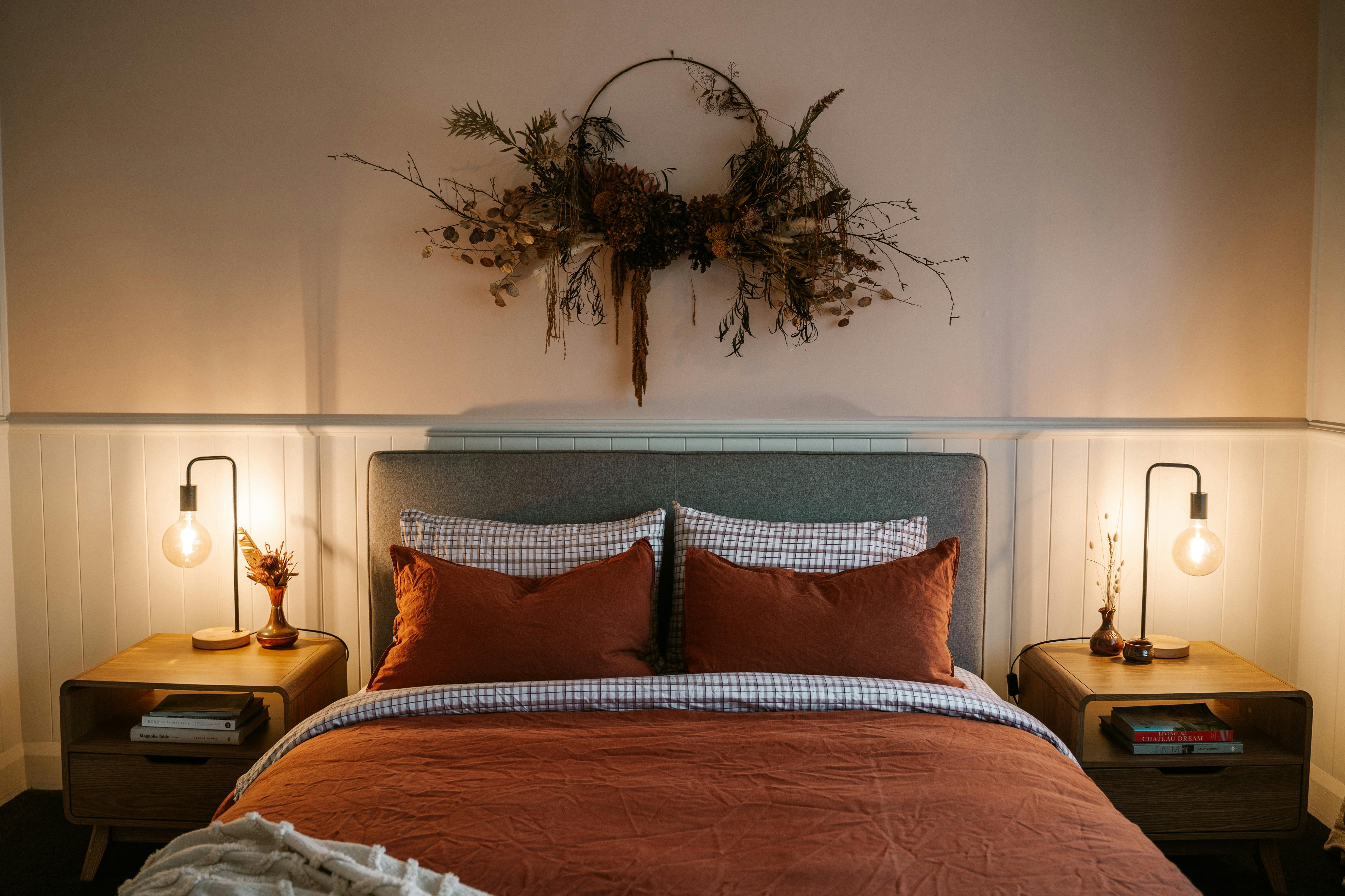 Bedside lamps a glow beside the queen size bed, with quality linen covers. dried flower decor.