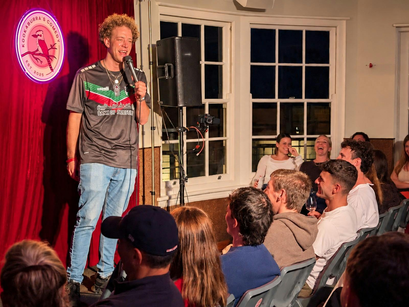 Stand-up comedian performing to a laughing crowd at The Nelson Hotel, Bondi Junction
