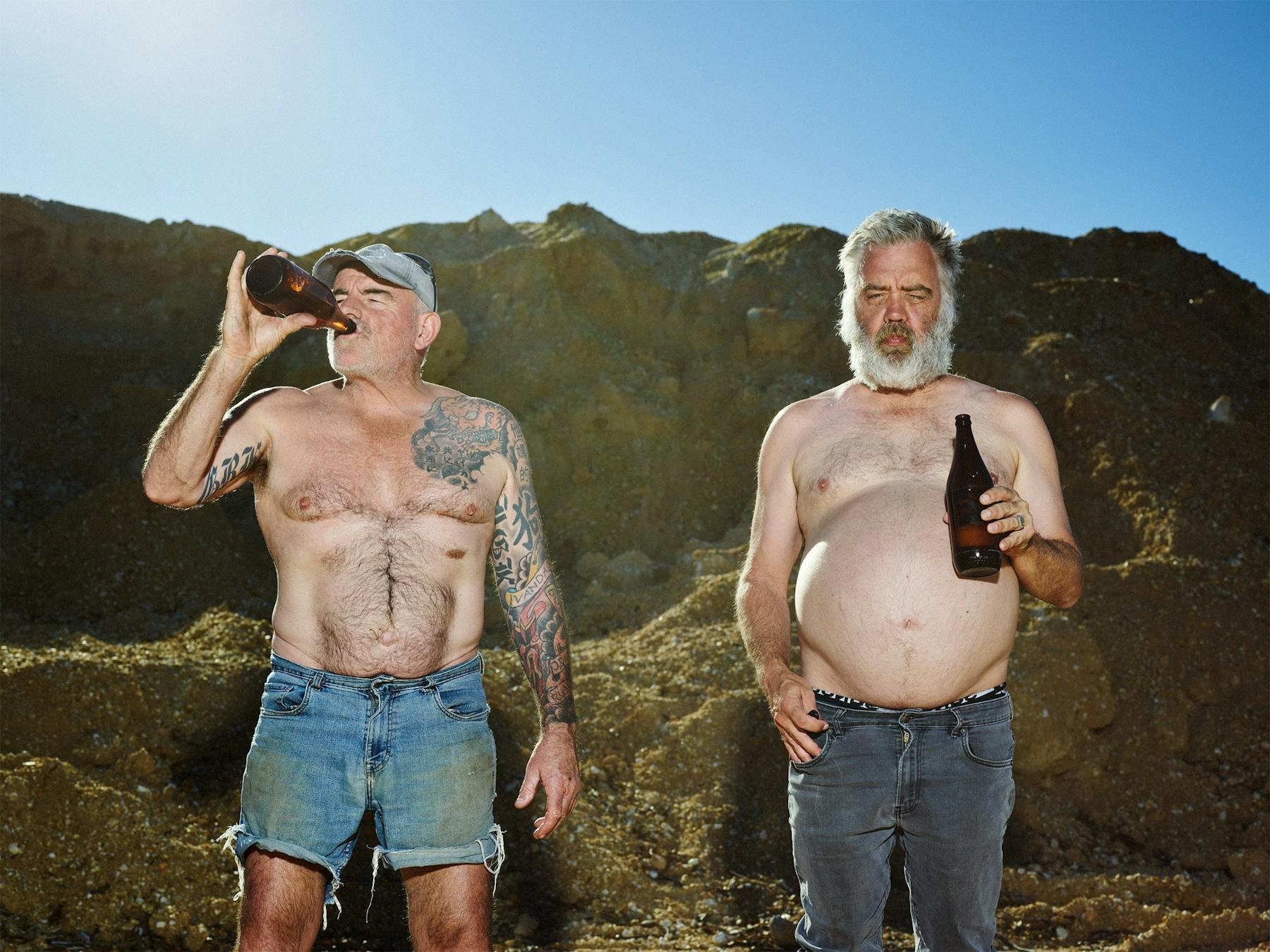 2 men pictured topless drinking beers