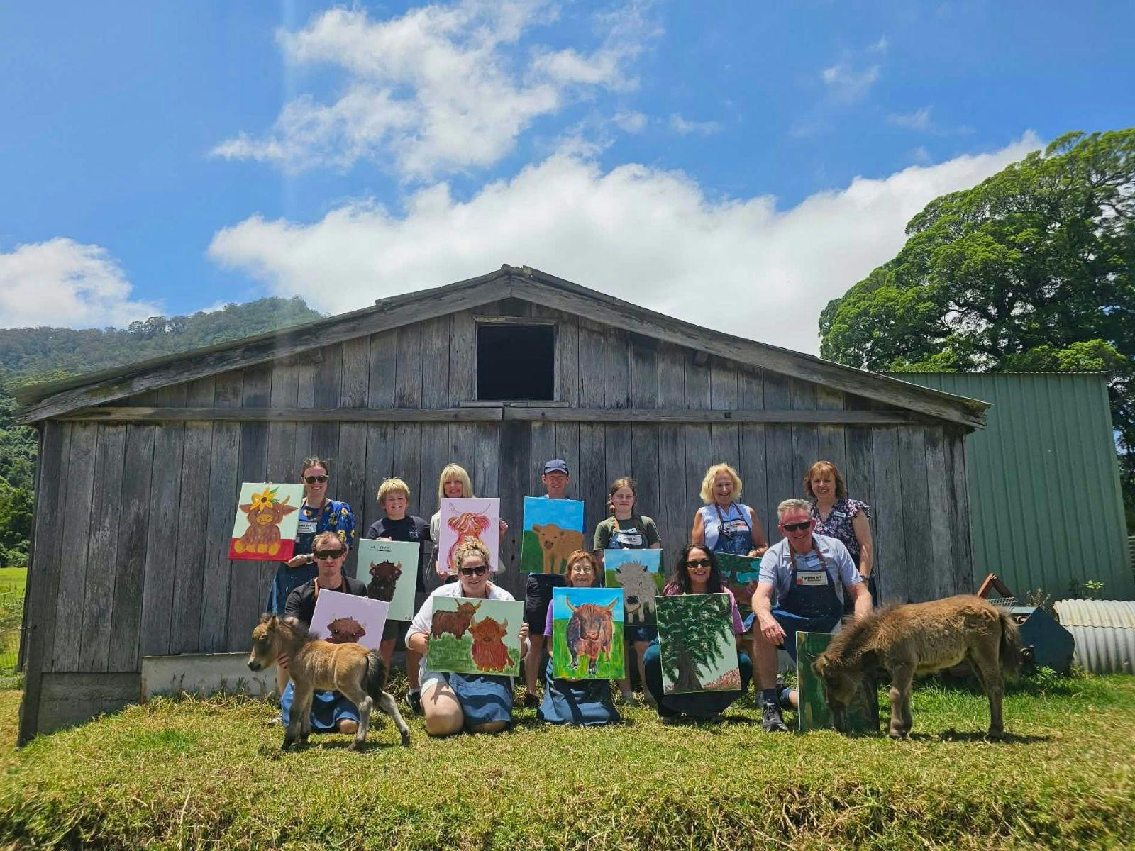 Group holding their complete Highland Cow painting in a paddock with 2 mini-horse foals