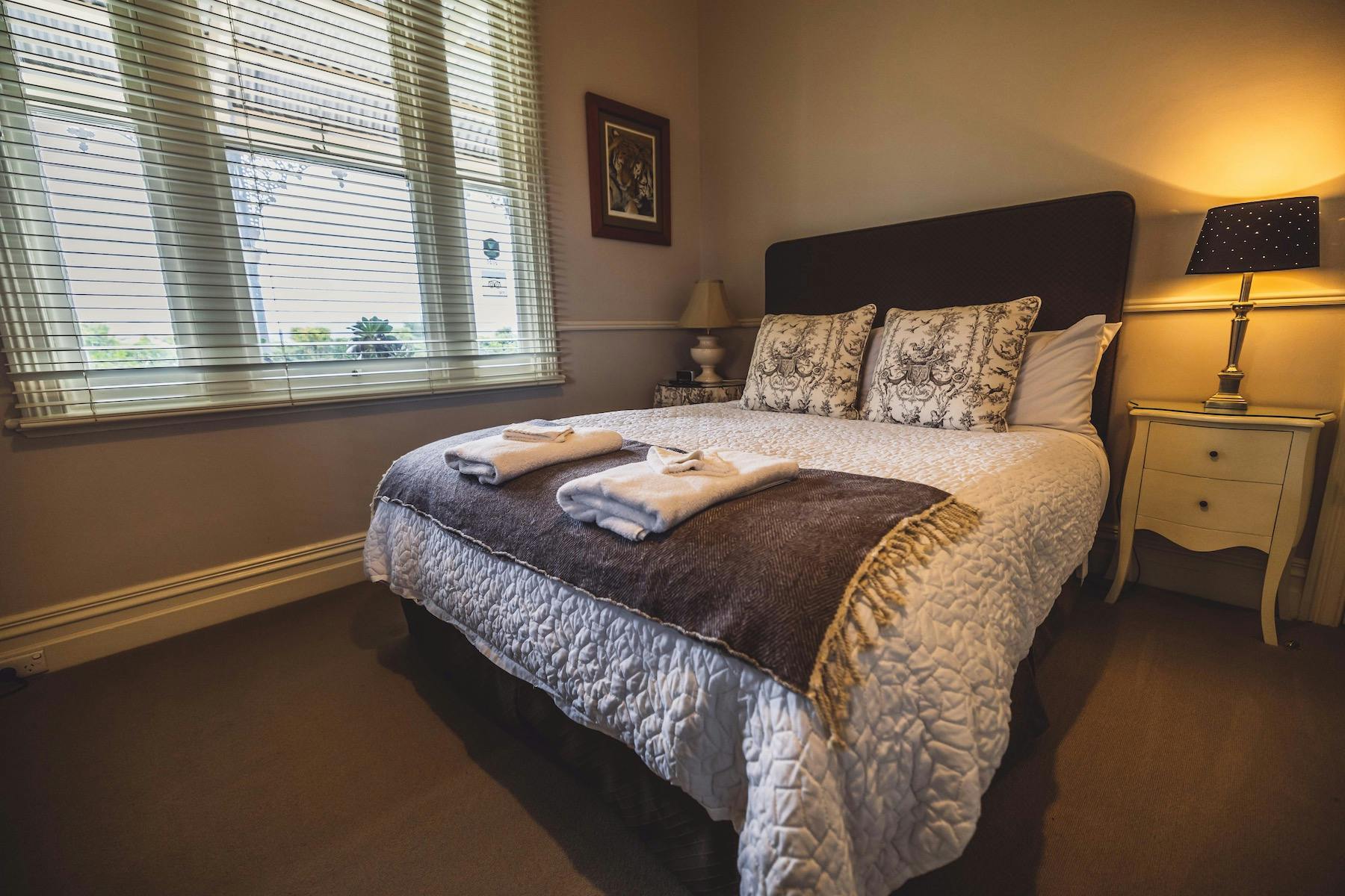 Brown Room with a neatly made bed, fresh towels and warm bedside lighting