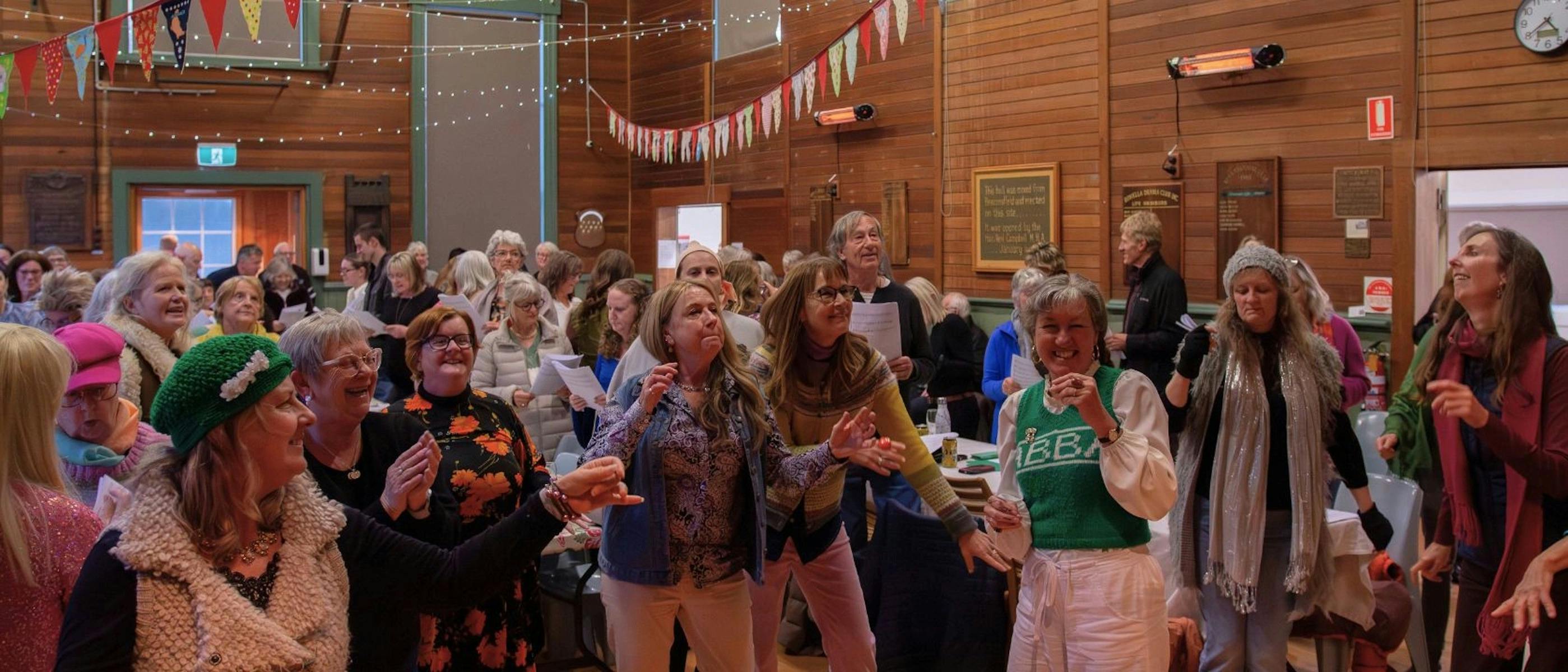 A group of people in a hall, dancing, singing and laughing.
