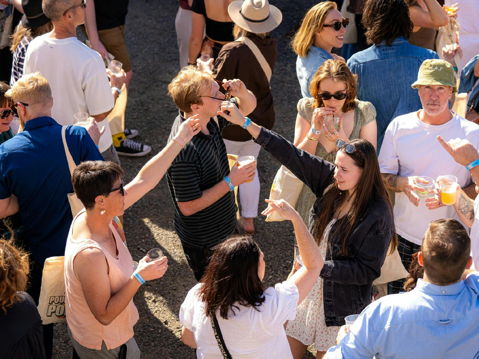 Taken from above, we see an enthusiastic crowd cheers glasses during Pours 2025