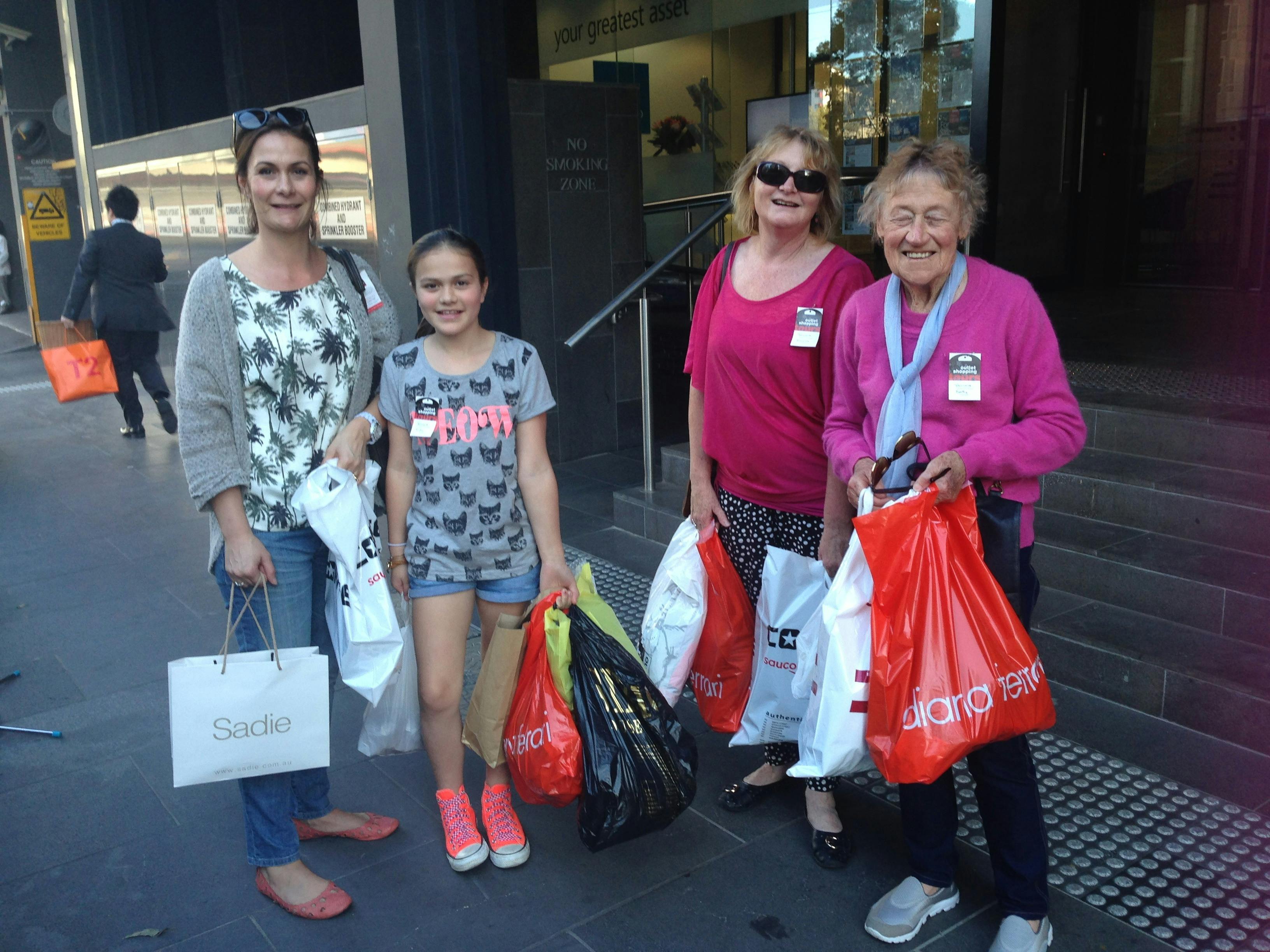 A group of women and a young girl holding shopping bags