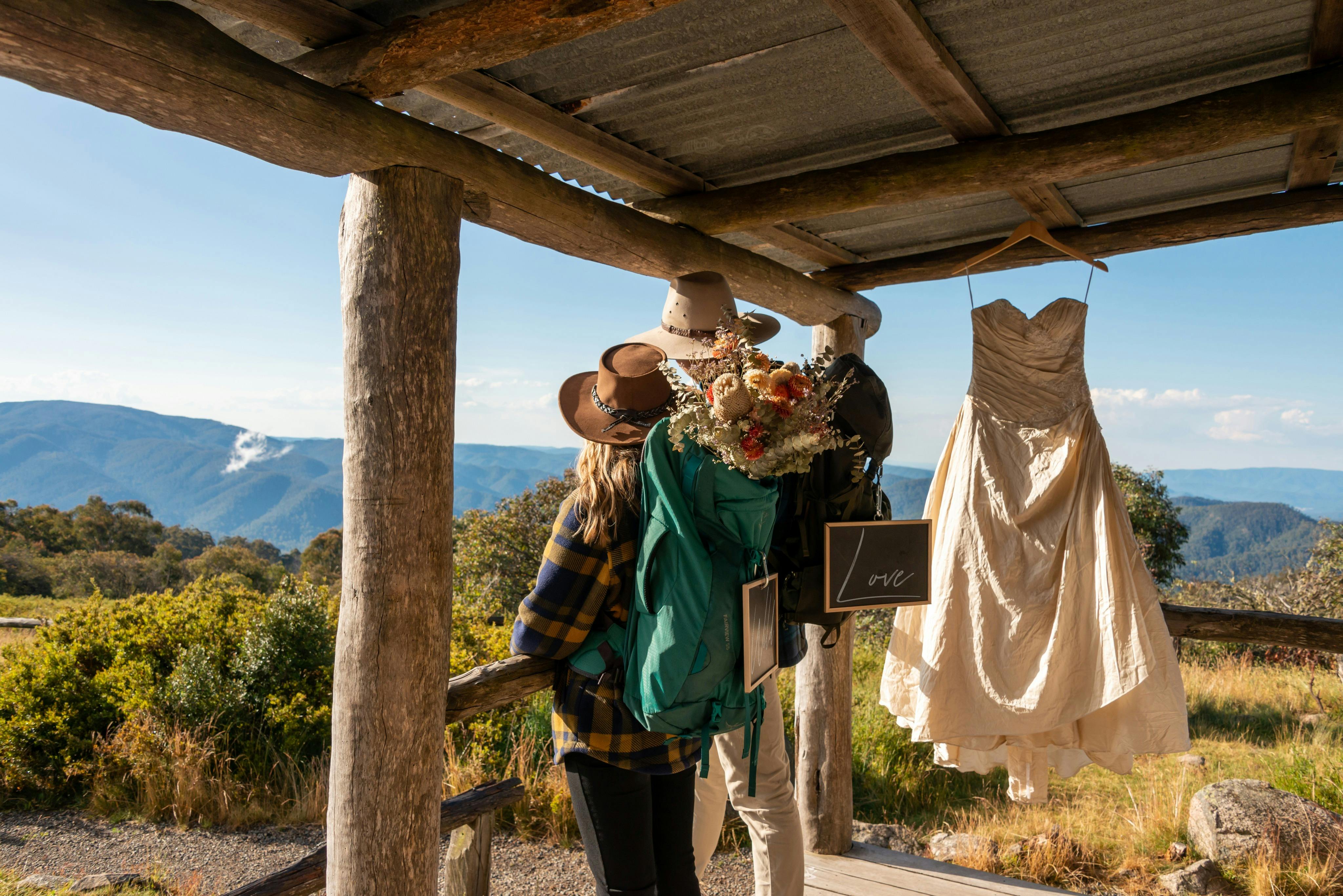 Bride and groom enjoying the views from Craig's Hut with the wedding dress hanging on the porch.