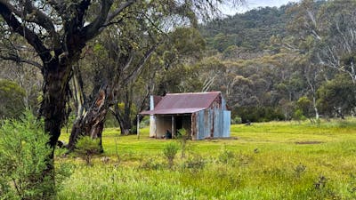 A metal hut in the middle of a grassy open plain.