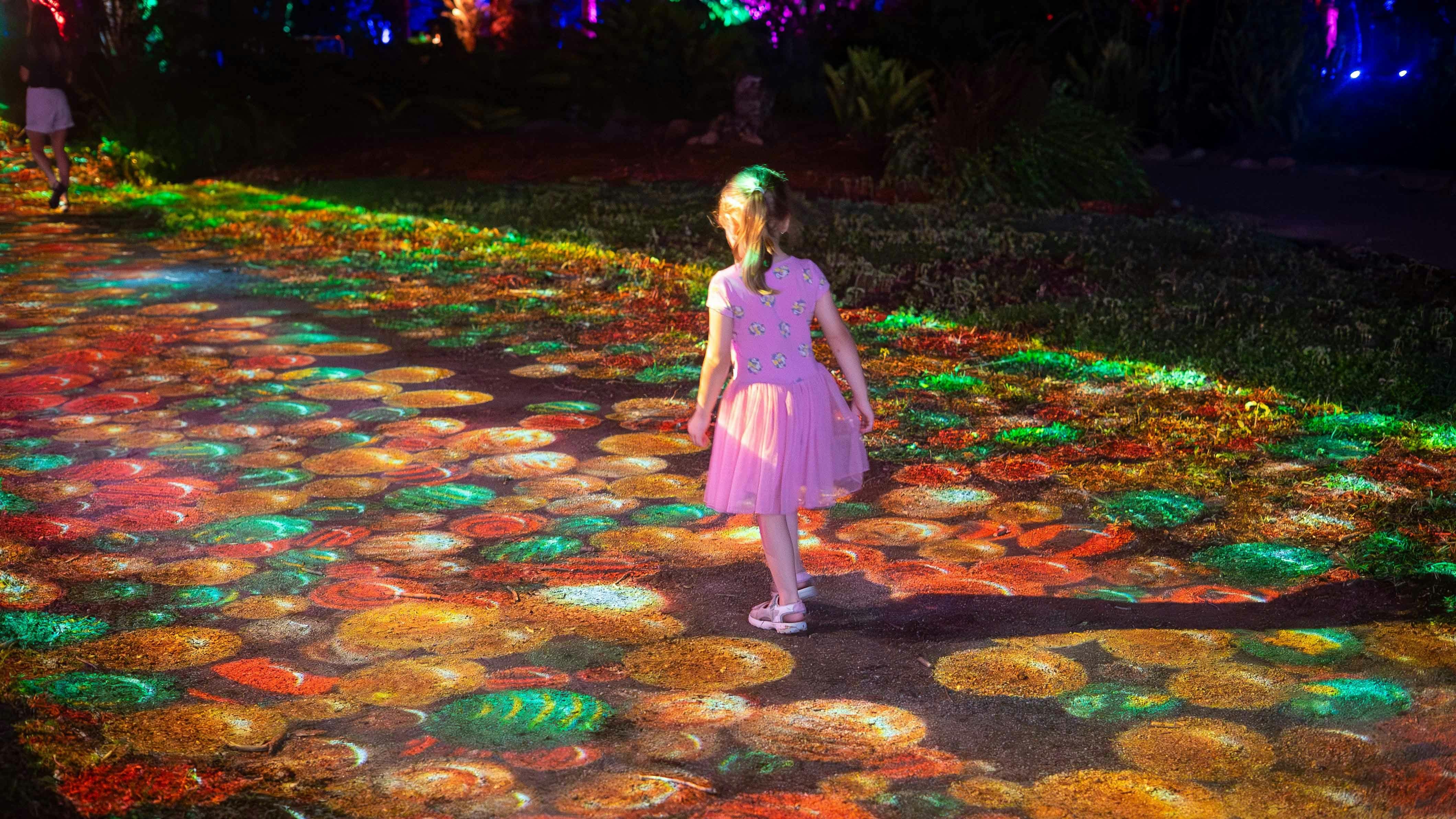 A child plays in the interactive projection of festive green, red and gold baubles at Radiance