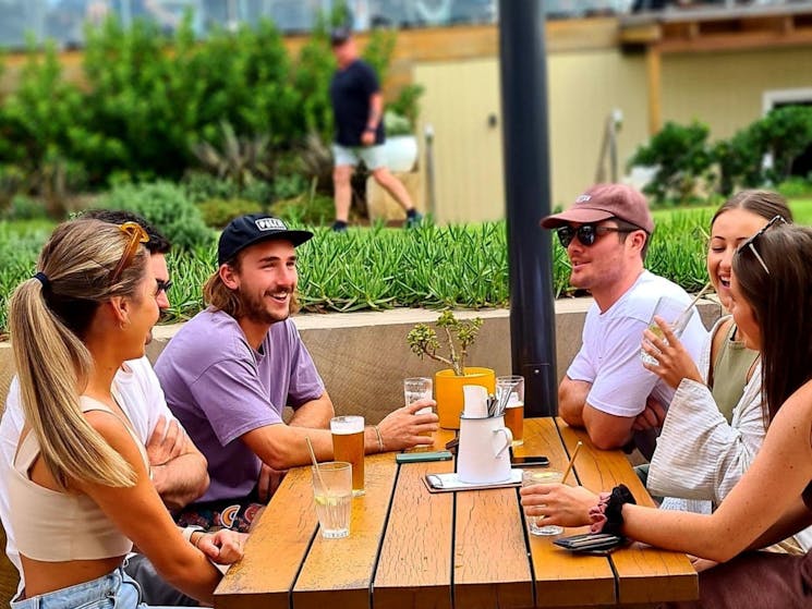 Group of friends ctaching up over beers at The Pavilion