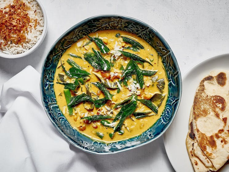 Yellow curry dressed with green beans in a deep blue bowl,on a white background at Rick Stein