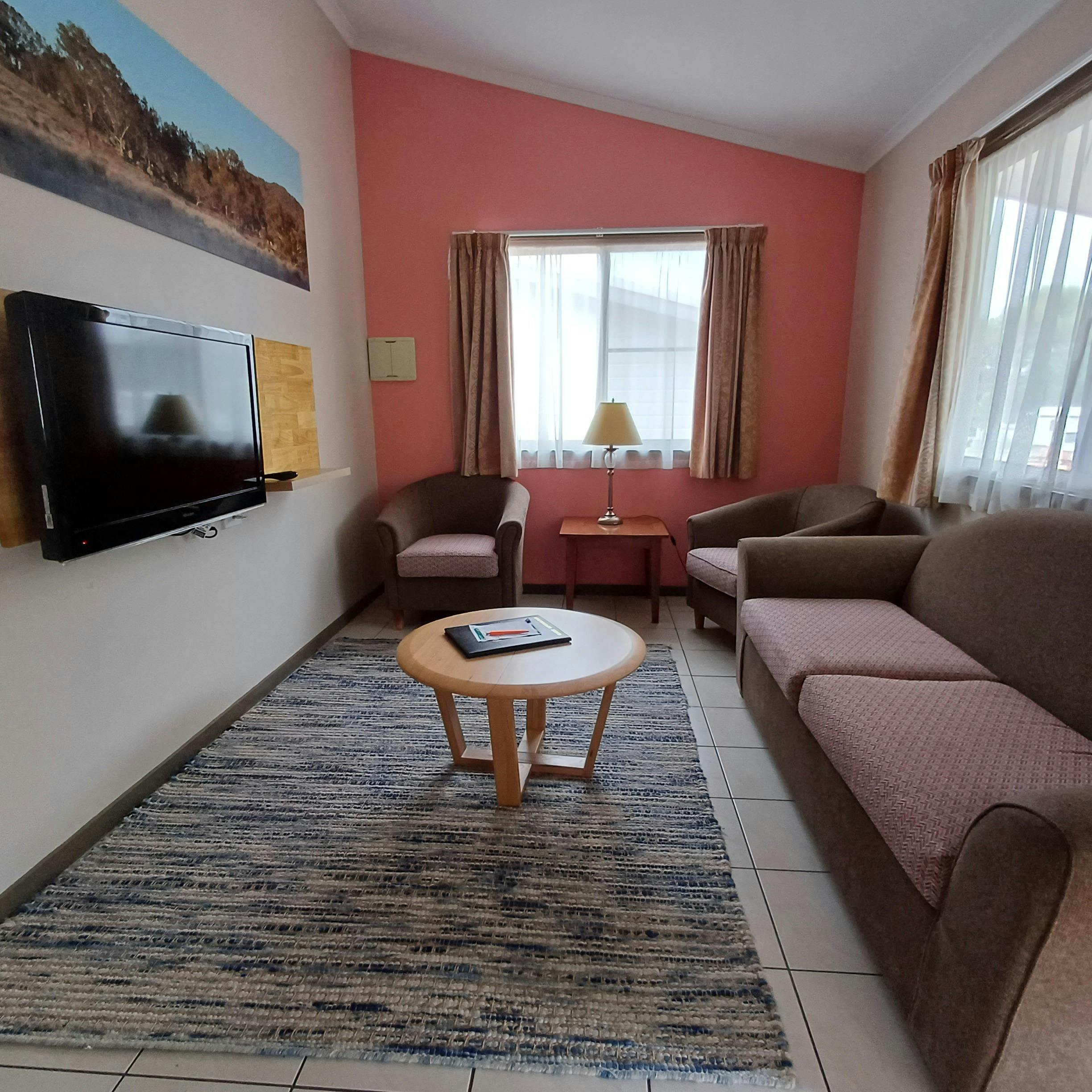 소파 2개, TV 커피 테이블 러그가 있는 라운지룸. 자연광이 풍부합니다.