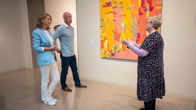 A gallery curator and couple standing in front of an artwork