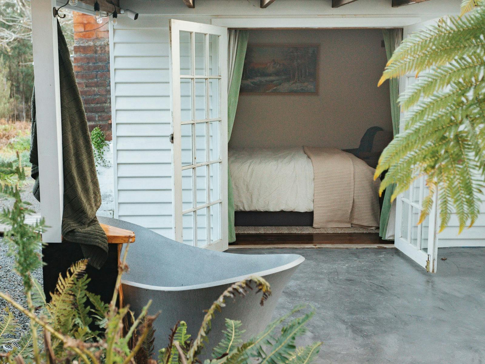 Outdoor bathtub on back deck with French doors into bedroom open.